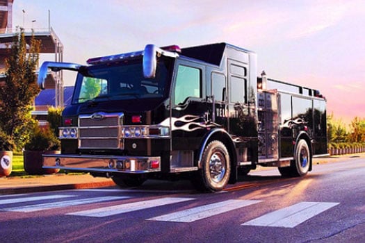 Black Pierce Manufacturing firetruck driving down the road on a sunny day.  