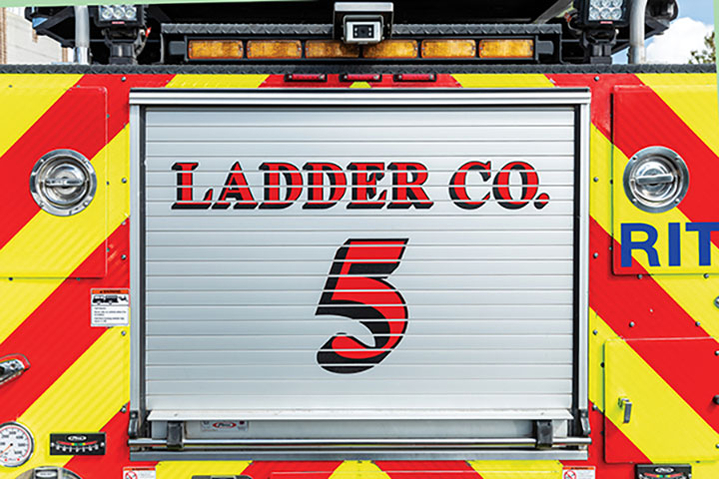 Rear compartment roll up door with custom graphics of an aerial ladder fire truck.