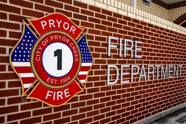 A brick wall with the Pryor Fire Department patch displayed as the fire department sign.