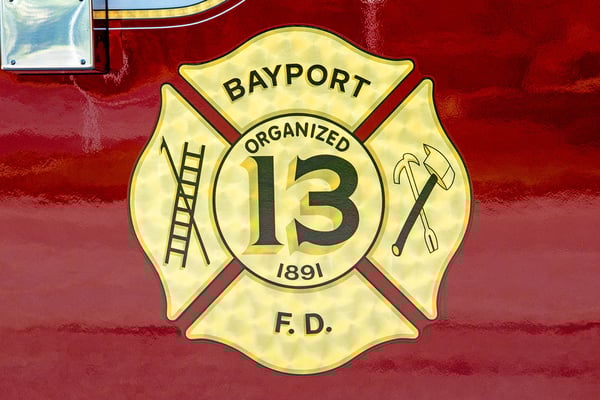 A gold patch graphic on a red fire truck door for Bayport Fire Department.