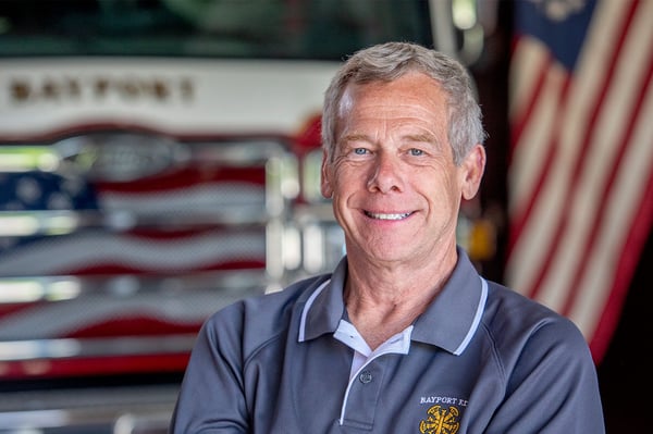 The fire chief for Bayport Fire Department in New York posed in front of a fire truck and an American Flag.