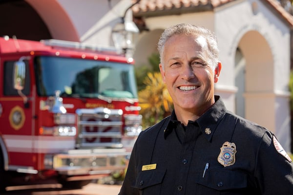 The fire chief for Montecito Fire Department posed in front of a fire truck at a fire station.