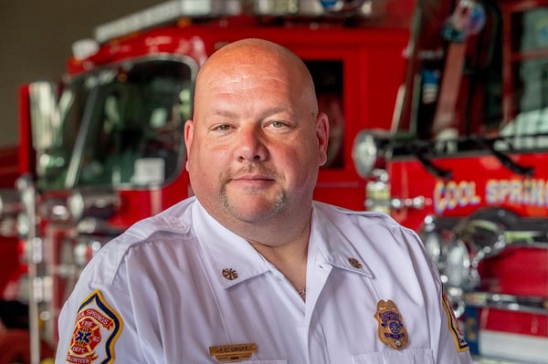 The Chief of the Cool Springs Volunteer Fire Department in North Carolina posing in front of fire trucks.