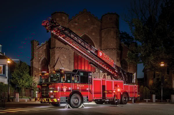 A 100 Heavy-Duty Low Profile Steel Aerial Ladder in front of a brick building at night with red lights.