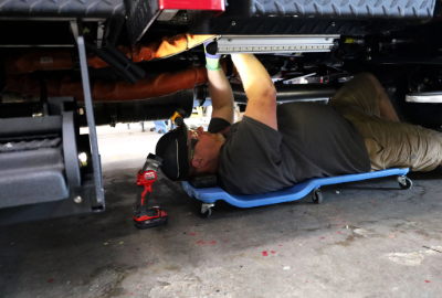 A man performing maintenance under the fire truck.