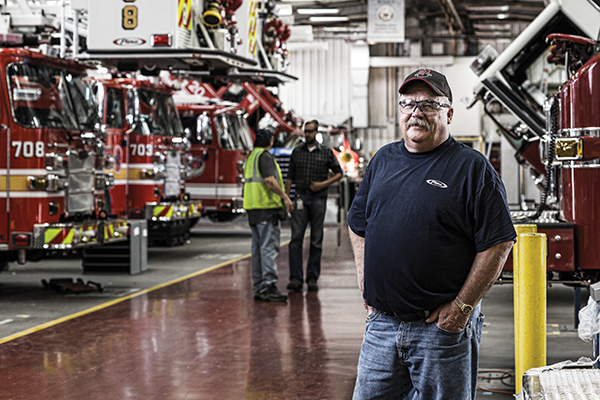 A Pierce worker standing near Pierce Fire Trucks on the production floor.