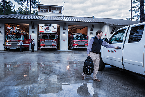 A Pierce dealer entering a Pierce company vehicle parked outside in front of a Fire Station.