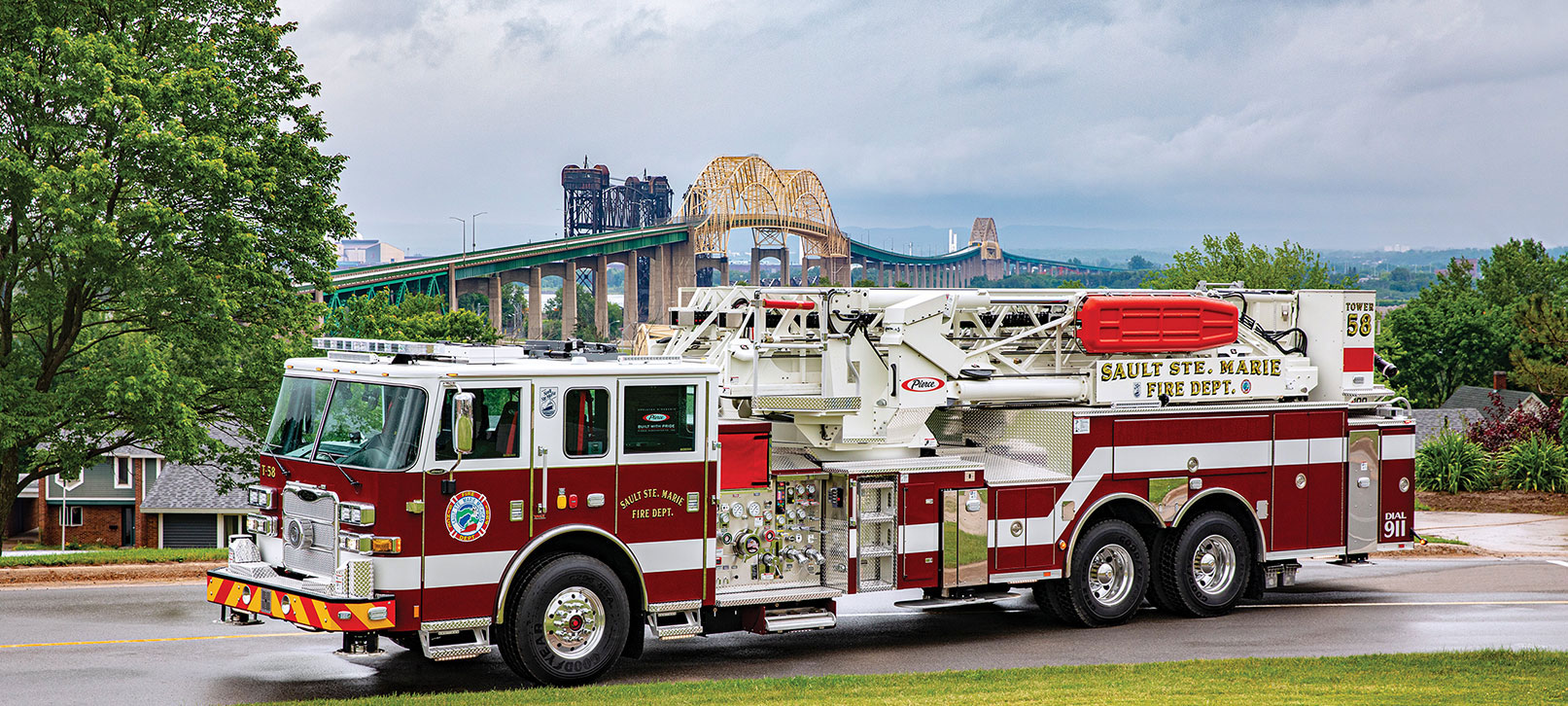 Pierce Aerial Fire Truck parked outside on the street near a bridge. 