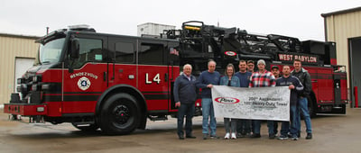 A team from West Babylon Fire Department is pictured holding a banner that says ‘200th Ascendant® 100 Heavy-Duty Aerial Tower’ as they stand in front of the apparatus at Pierce Manufacturing. 