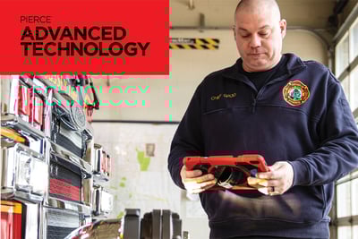 A man stands next to a roll up garage door and fire truck supplies holding a red iPad. Pierce Advanced Technology is written in black on a red rectangle in the top left corner.