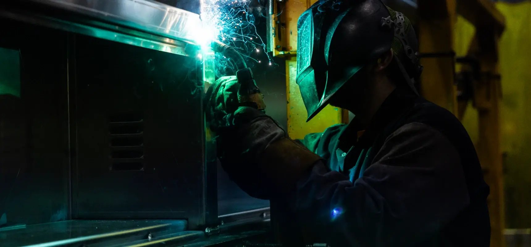 A welder at Pierce Manufacturing works on metal fabrication, generating bright sparks.