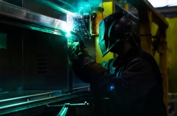 A welder at Pierce Manufacturing works on metal fabrication, generating bright sparks.