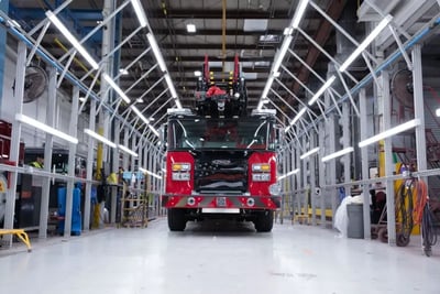 A red Pierce fire truck inside an advanced paint inspection light tunnel for quality control.