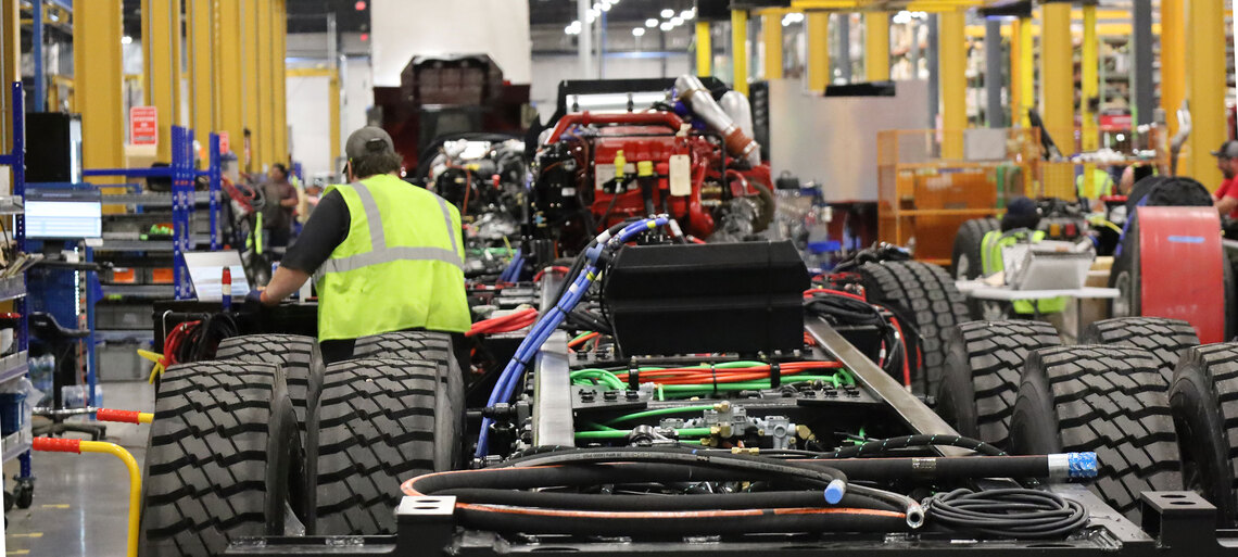 A fire truck manufacturing facility with a team member working on a fire truck chassis and frame-rails.