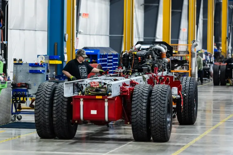A technician works on a heavy-duty fire truck chassis during the assembly process.