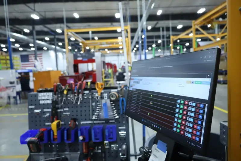A computer monitor displays the Truck Builder system in a fire truck chassis assembly facility.