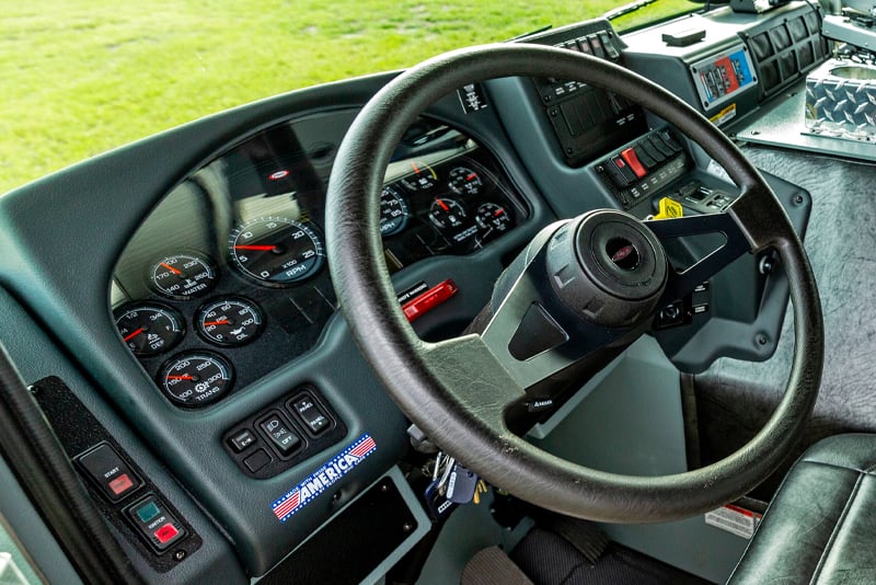 The interior of a Pierce Manufacturing fire truck cab shows a close up of the steering wheel and system gauges.