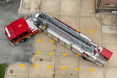 A red and white tractor drawn aerial is shown from an overhead view to see the jackknife position that shows the great maneuverability of the truck design.  
