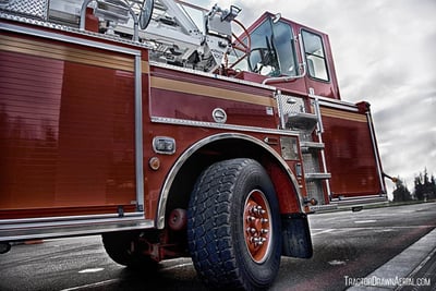 A close up of a tiller cab on a red tractor drawn aerial fire truck is isolated in on outdoor environment.