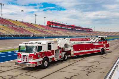 A white and red tractor drawn aerial is parked in a stadium with yellow and red stands in the background. 