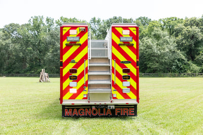 The red and yellow chevon rear end of a rescue fire truck features a build in rear staircase to access the top of the truck.