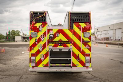 The rear end of the fire truck shows the folding steps to access the top, available storage and the required lighting and red and yellow chevron striping.
