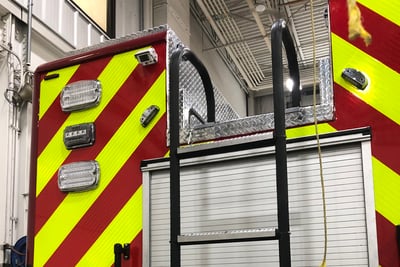 A fire truck slide-out ladder is pulled down and ready for use on the rear of a firetruck.