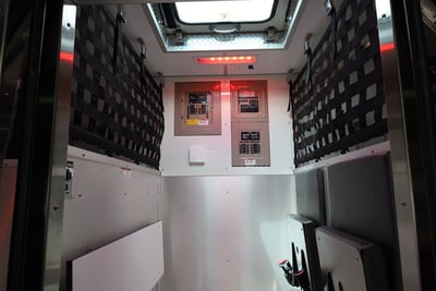 A climate controlled compartment on a fire truck shows black webbing to secure tools and equipment at the top and open space at the bottom. 