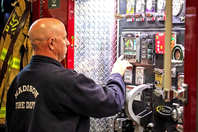 A Madison Fire Department firefighter is using the touchscreen on an exterior fire truck panel. 