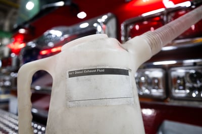 A tank of diesel exhaust fluid on the bumper of a fire truck.