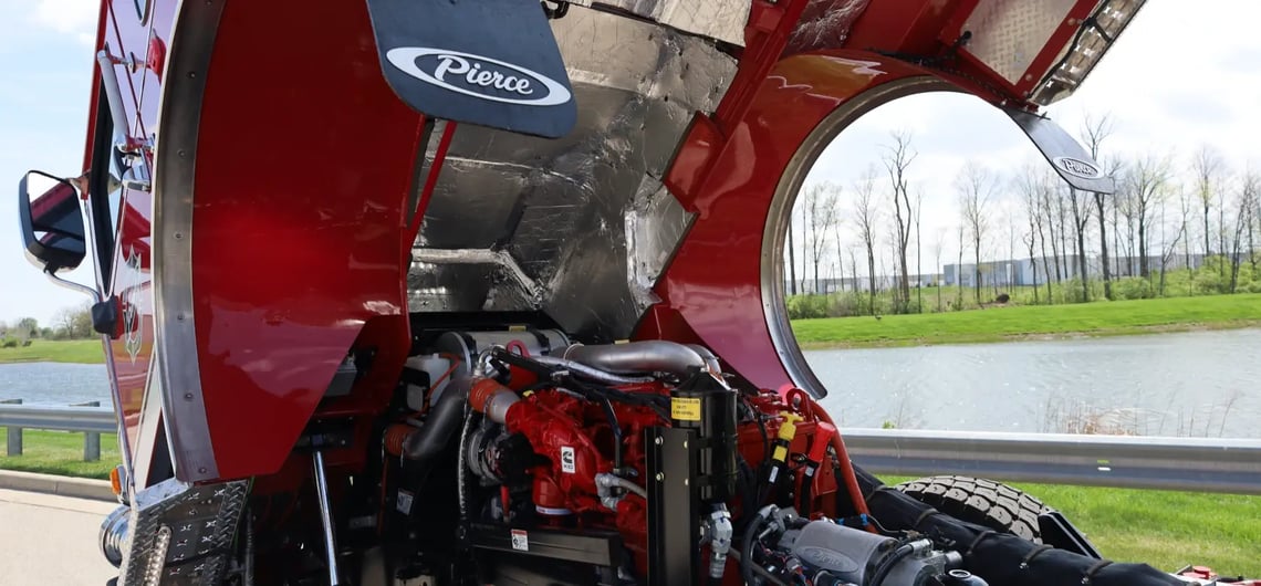 A Cummins X10 engine is visible inside the tilted open hood of a red Pierce fire truck.