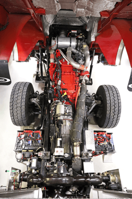 Top-down view of a fire apparatus diesel engine and exhaust aftertreatment system on a chassis.