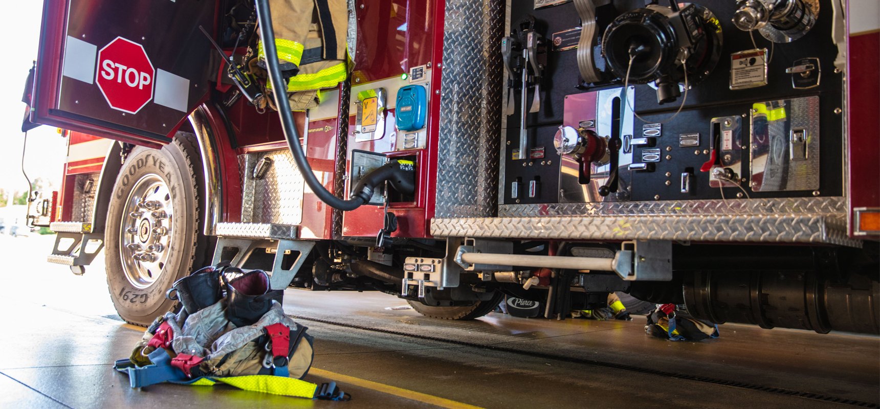 A close up view of a fire truck driver’s side showing the electric fire truck charger connected and the fire truck panel.