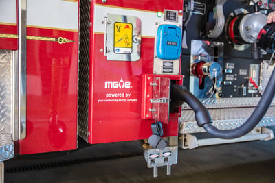 A close up image shows the plug powering up a red electric fire truck.