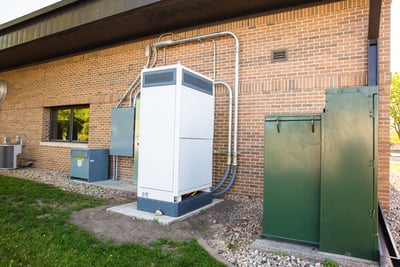 The exterior of a fire station shows the placement of a white high-voltage cabinet that is used to power an electric fire truck. 