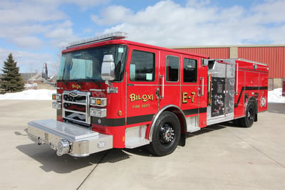 The red Pierce Manufacturing fire truck built for Biloxi fire department is parked outside in winter with a industrial facility visible in the background.