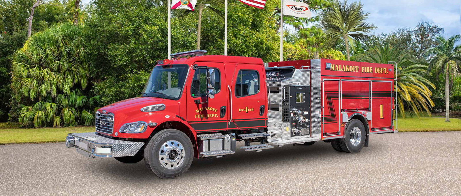 The Malakoff Volunteer Fire Department red and white pumper fire truck is parked on asphalt in a warm climate showcasing the driver side features.