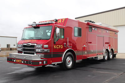 A red hazmat fire truck is parked outside of a manufacturing facility. 