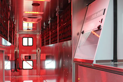 The walk-in interior space of a hazmat fire truck is lighted red and shows the technology and compartments included on board. 