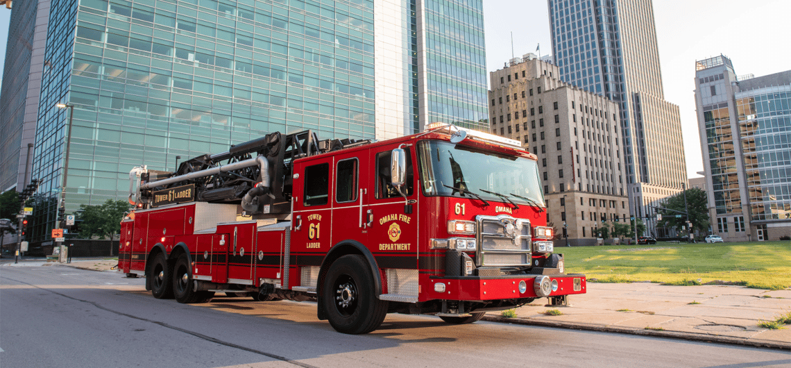 Omaha Fire Department Pierce aerial fire truck in an urban setting with skyscrapers.