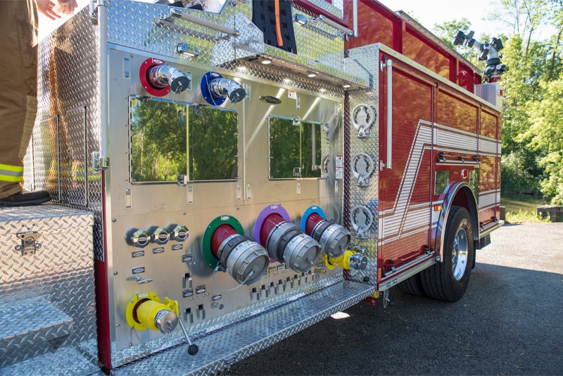 A pump panel is pictured on a red industrial fire truck.