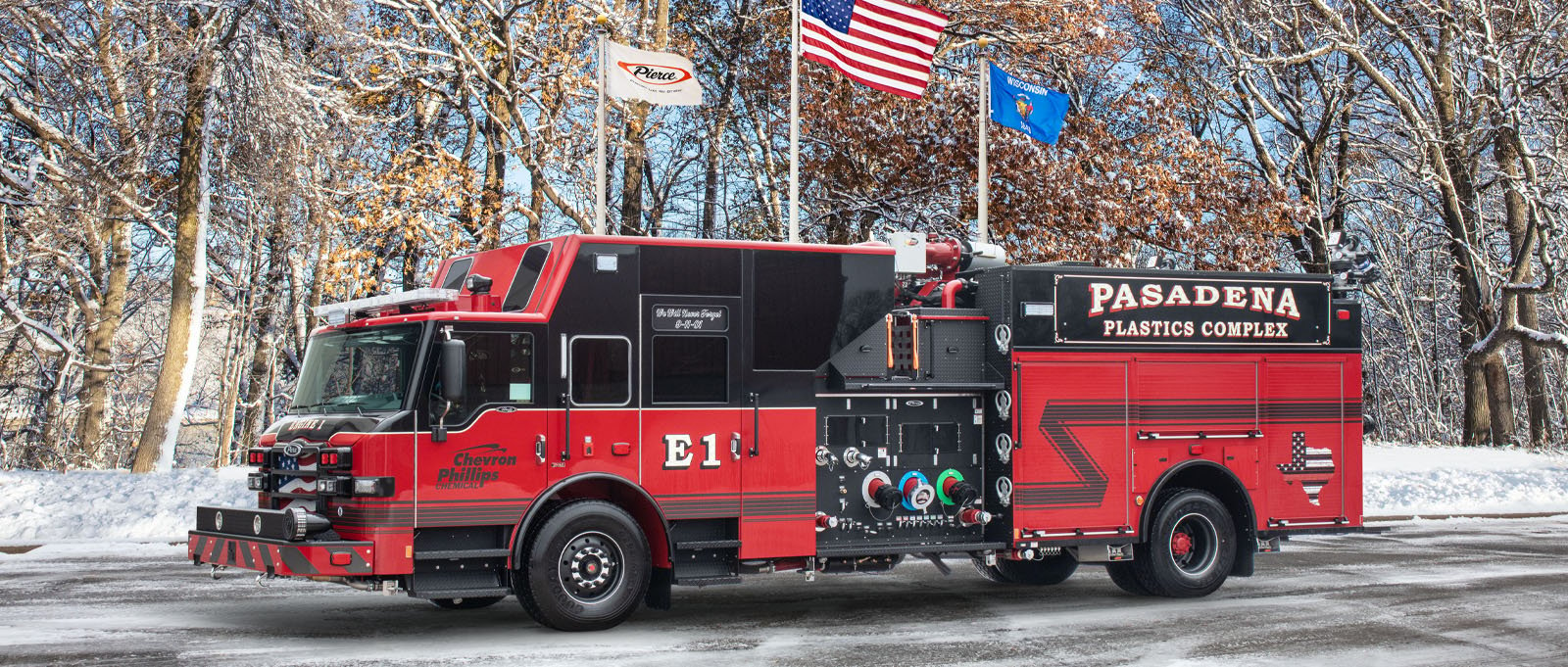 The Pasadena industrial pumper truck is pictured in winter in front of flags in the Pierce Manufacturing parking lot.