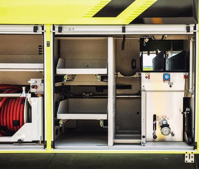 A close up image of the compartment space on a yellow and black Striker airport fire truck.