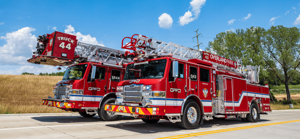 Two Overland Park Pierce aerial fire trucks, a quint and a platform truck, parked side by side.
