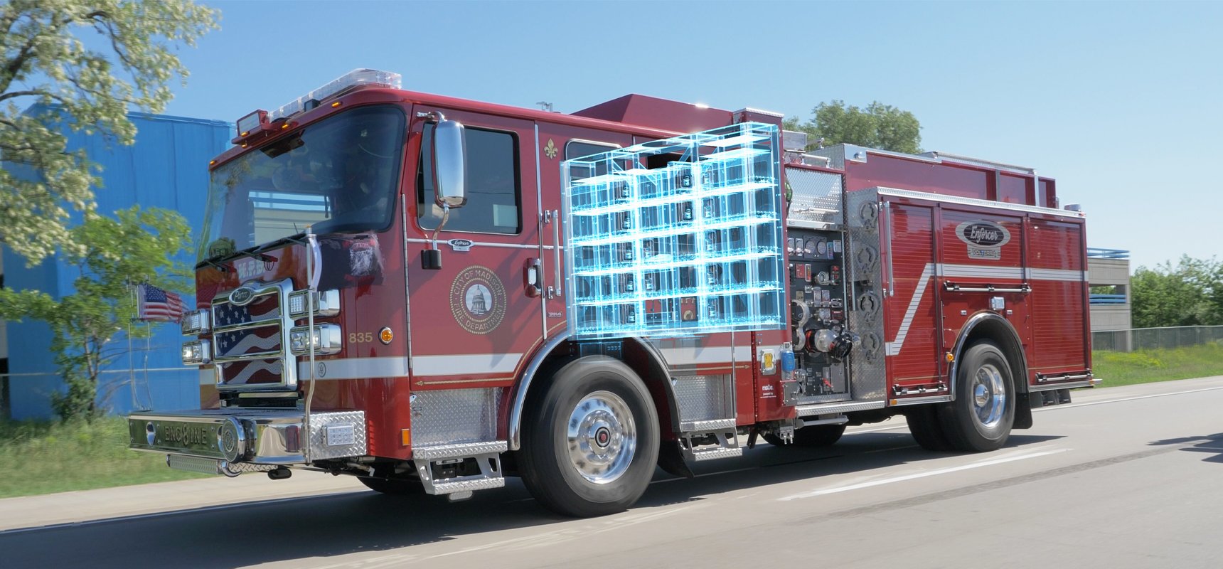 A red electric fire truck drives along a highway with the patented parallel-electric drive train highlighted with a graphic overlay.
