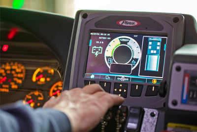 An operator uses a touch screen inside an electric fire truck cab to monitor and use the technology. 