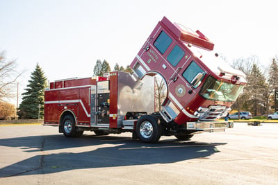 An electric fire truck is parked and pictured with the cab tilted, revealing no engine.