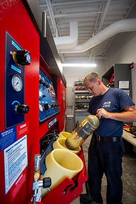 A firefighter places a soiled SBCA unit into a decontamination unit inside the fire house. 