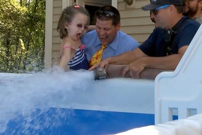 Members of the Essex Fire Department fulfilling Addi Carroll's Make a Wish Foundation wish by filling her swimming pool with a fire truck hose.