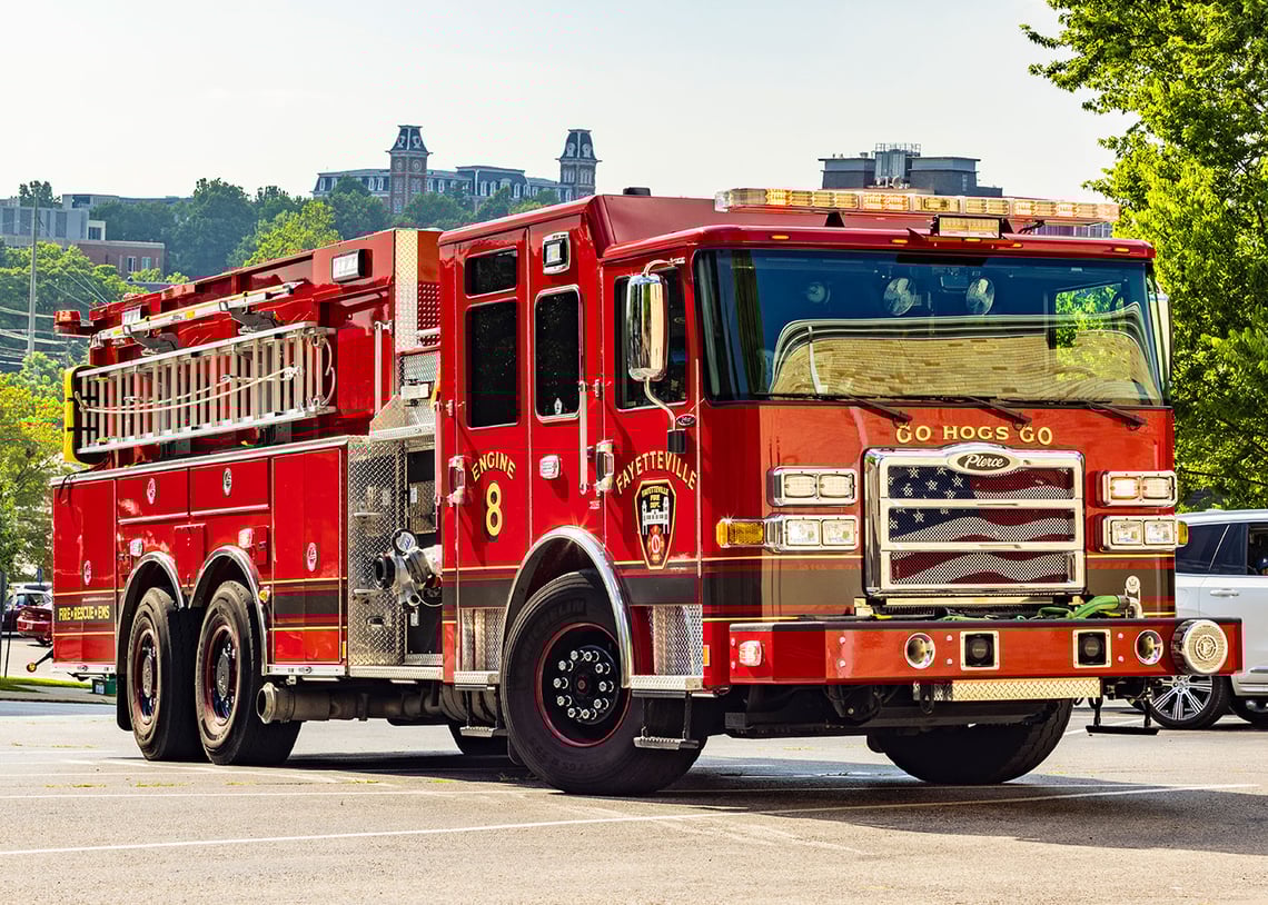The front officers side of a custom dry-side tanker driving through a parking lot.